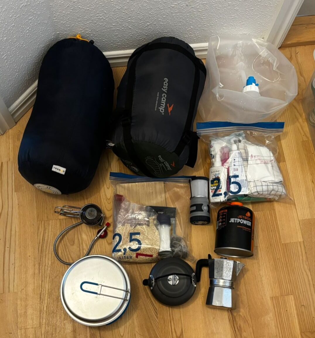 Essential camping gear including sleeping bags, cooking equipment and water container